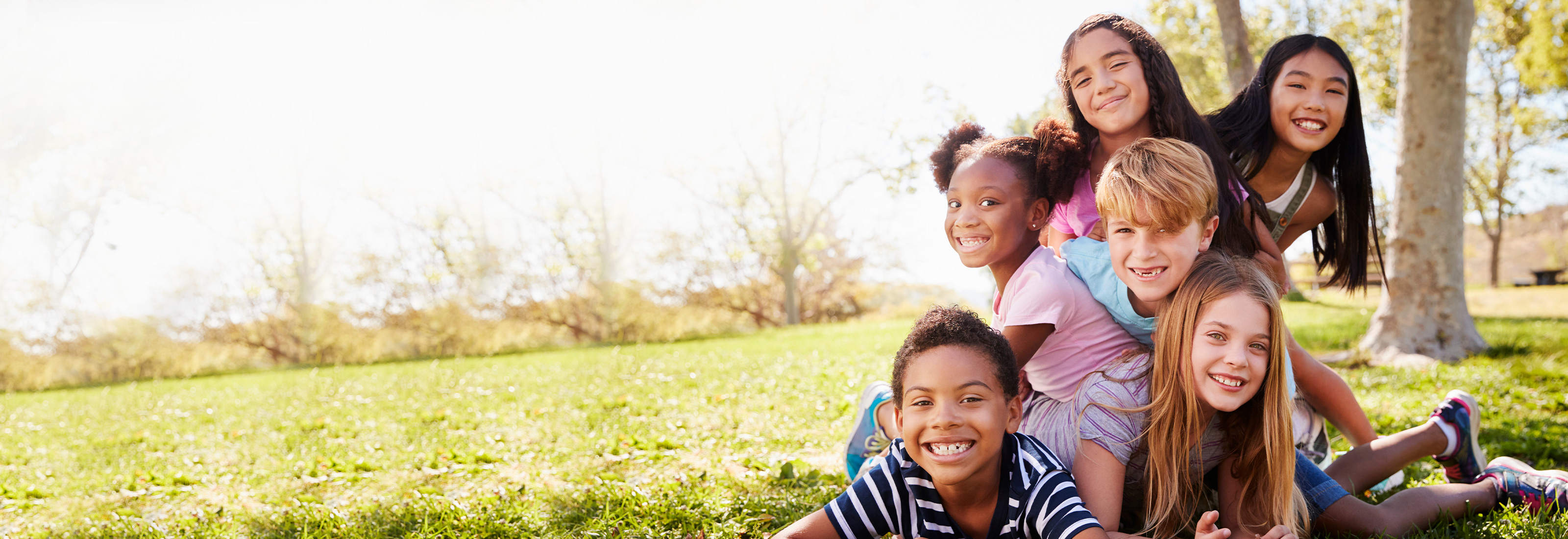 Kids outside in front of a tree.